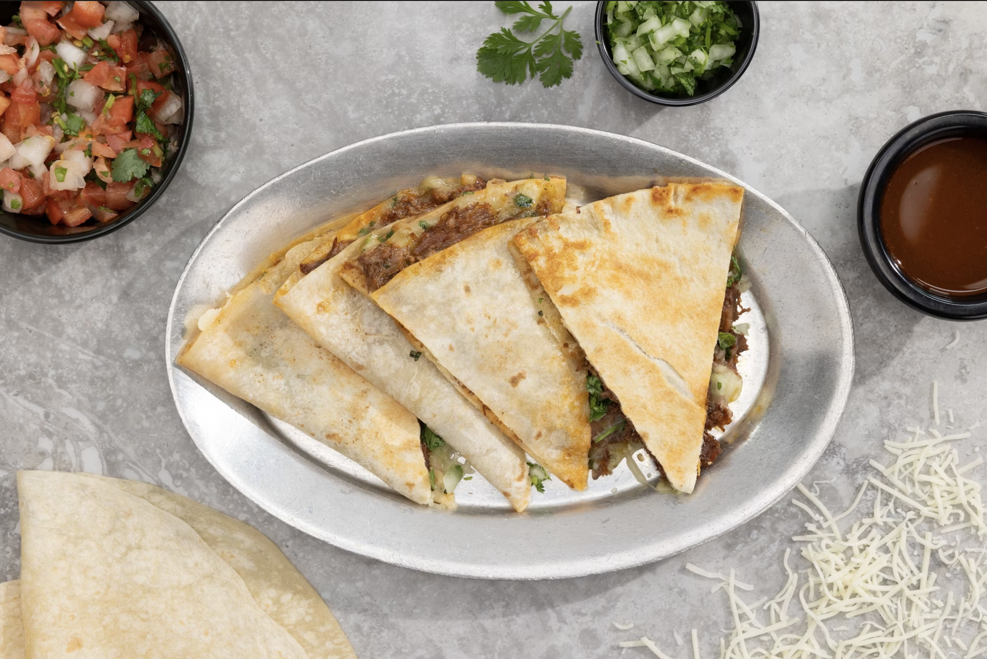 Quesabirria quesadilla on a plate with consome dip on the side