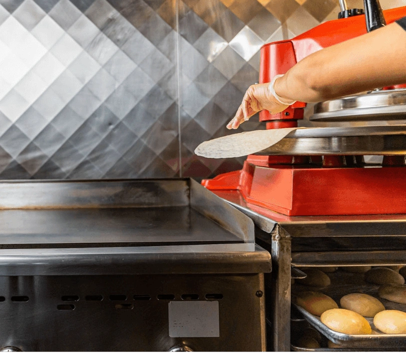Flinging a fresh-pressed tortilla off of the press and onto the grill